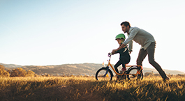 un père qui apprend à son enfant à faire du vélo